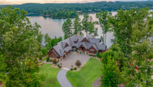 a large house with a large driveway surrounded by trees and a lake